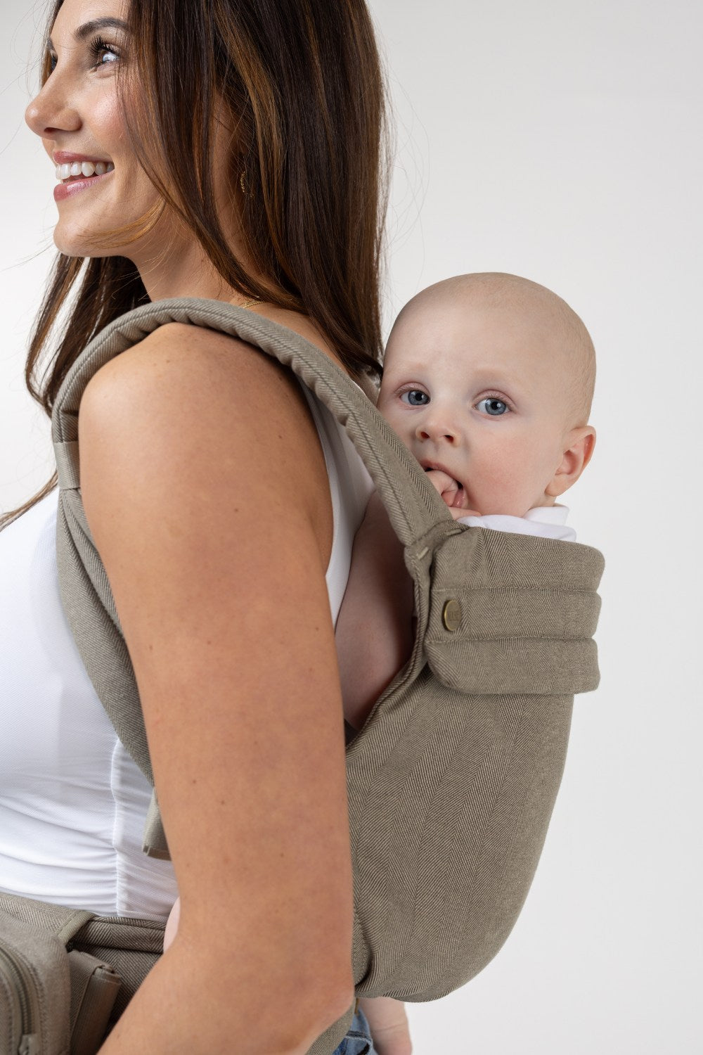 The Mabē Monarch Buckle Carrier in Charles Herringbone, which is a delicate herringbone weave cotton/linen fabric in shades of brown worn by a woman with the baby on her back.