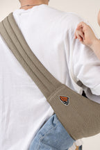 Unseen child in the Mabē Monarch Toddler Sling in Charles Herringbone, which is a delicate herringbone weave in shades of brown, worn by an unseen adult.