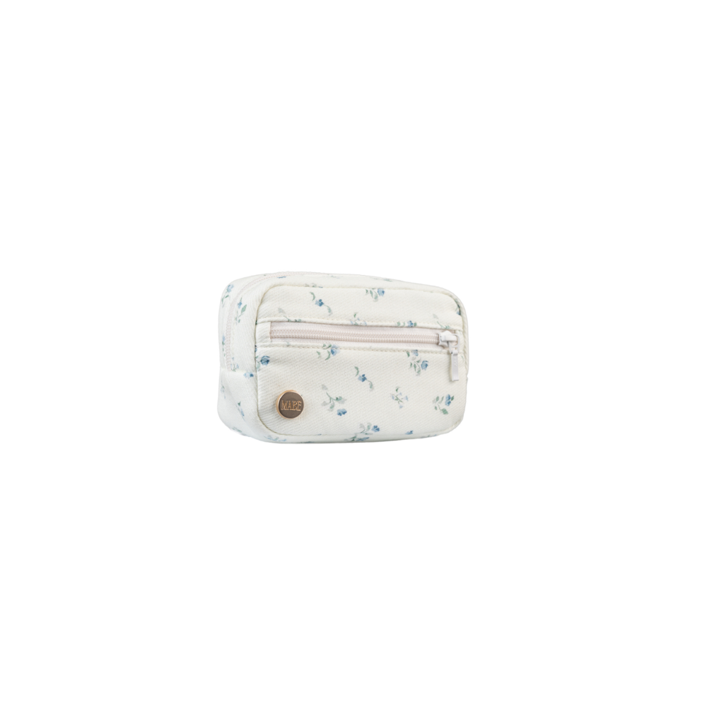 Photo of the Mabē Monarch Accessory Bag in Sunday Floral, which is white with delicate sprigs of blue flowers. There is a gold branded button on the lower left of the bag, and two zippered pockets.