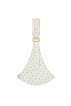 The Mabē Monarch Toddler Sling in Sunday Floral, white cotton/linen fabric with delicate sprigs of blue flowers, gold branded button and ladder lock buckle, and quilted crossbody shoulder strap.