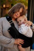 A mom cuddles her toddler on her hip in the Mabē Monarch Toddler Sling in Ebony.