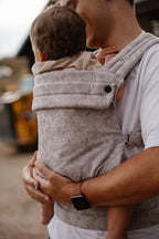 A dad wears his baby in the Mabē Monarch Baby Carrier in Ashland Camo, side view showing the light gray camo print.