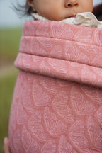 Close-up of the textured blush pink butterfly print on the Mabē Monarch Baby Carrier in Mauve Wings.